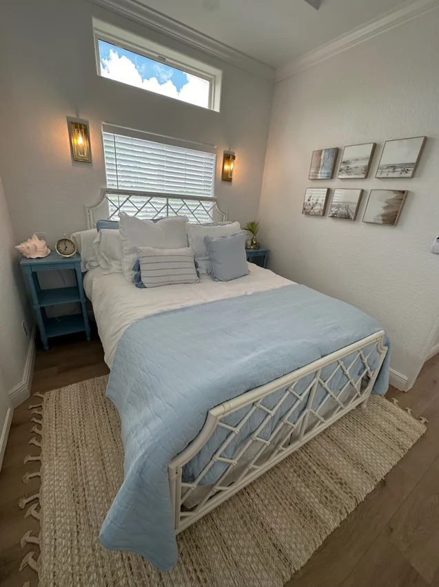 The bedroom with pale blue bedding, bedside tables and tall windows.